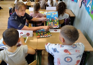 policjantka przekazuje książeczki dzieciom