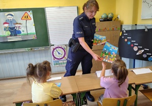 policjantka przekazuje książeczki dzieciom