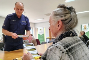 policjant przekazuje ulotkę seniorce