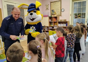 policjant rozdaje dzieciom książeczki