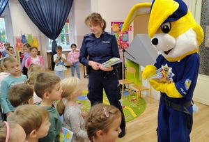 policjanta rozdaje dzieciom książeczki