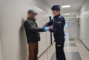 umundurowany policjant zakłada kajdanki zatrzymanemu
