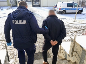 policjant prowadzi poszukiwanego mężczyznę