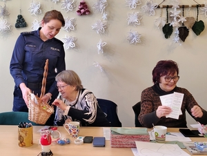 policjanci wraz z młodzieżą rozdają ulotki i odblaski seniorom