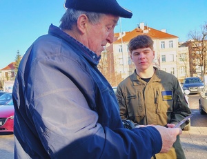 policjanci wraz z młodzieżą rozdają ulotki i odblaski seniorom