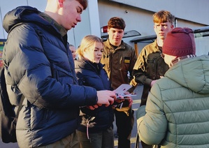 policjanci wraz z młodzieżą rozdają ulotki i odblaski seniorom