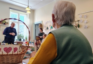 policjanci wraz z młodzieżą rozdają ulotki i odblaski seniorom