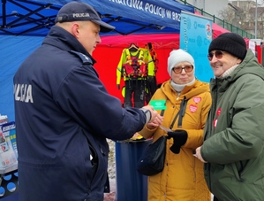 policjant przekazuje ulotki seniorom