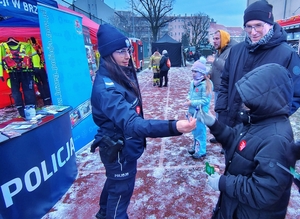 policjant przekazuje ulotki seniorom