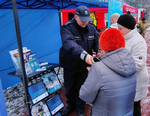policjant przekazuje ulotki seniorom