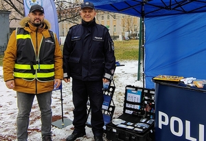 na tle niebieskiego namiotu stoją osoby