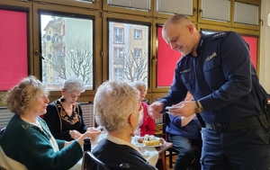 policjant przekazuje elementy odblaskowe seniorom