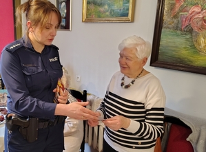 policjantka przekazuje opaski odblaskowe seniorom