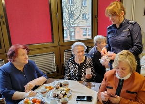 policjantka przekazuje opaski odblaskowe seniorom