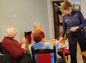 policjantka przekazuje opaski odblaskowe seniorom
