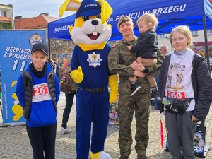 policyjna maskotka i osoby z nim pozujące do zdjęcia