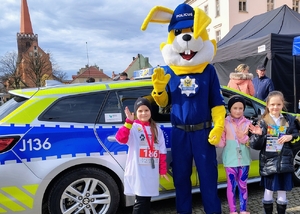 policyjna maskotka i osoby z nim pozujące do zdjęcia