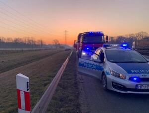 radiowóz na jezdni, za nim wóz strażacki