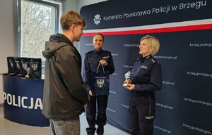 młodzież z policjantką na tle granatowego baneru