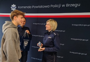 młodzież z policjantką na tle granatowego baneru