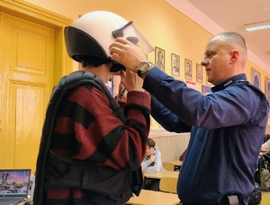policjant ubiera nastolatkowi sprzęt antyuderzeniowy