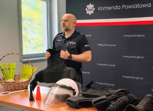 policjant trzyma kamizelkę kuloodporną