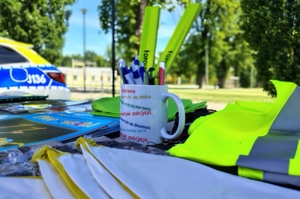 kubek, odblaski, ulotki na stoliku, w tle zielona trawa