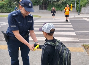 policjantka przekazuje element odblaskowe dzieciom