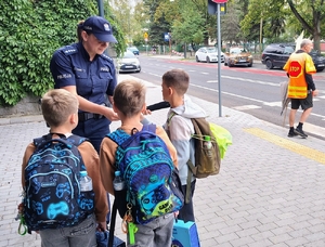 policjantka przekazuje element odblaskowe dzieciom