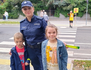 policjantka przekazuje element odblaskowe dzieciom