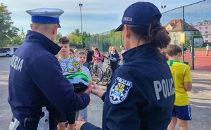 policjant przekazuje kask rowerowy