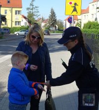 Policjanci rozdają dzieciom i rodzicom odblaski i odznaki &quot;Jestem bezpieczny – jeżdżę w foteliku&quot;