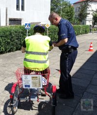 w obecności policjanta młodzież na rowerach korzysta z miasteczka ruchu drogowego