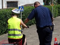 w obecności policjanta młodzież na rowerach korzysta z miasteczka ruchu drogowego