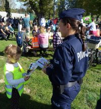 policjanta rozdaje dzieciom książeczki &quot;Bezpieczny Przedszkolak&quot;