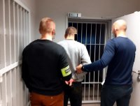 nieumundurowani policjanci prowadzą zatrzymanego w kajdankach