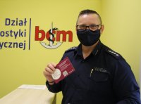 policjant na tle szyldu Dział Diagnostyki Medycznej BCM