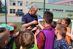 policjant przekazuje odblaski dzieciom