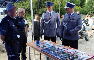 policjanci rozmawiają przy stanowisku ze sprzętem i materiałami promocyjnymi