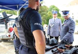 policjanci rozmawiają przy stanowisku ze sprzętem i materiałami promocyjnymi