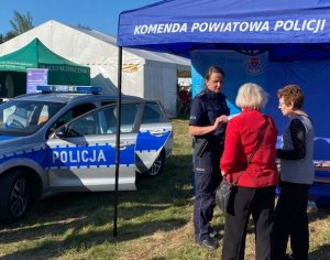 policjantka rozmawia z osobami przy namiocie z materiałami profilaktycznymi